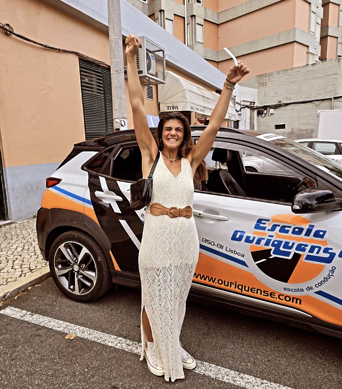 Aluna a celebrar a aprovação junto à viatura da escola